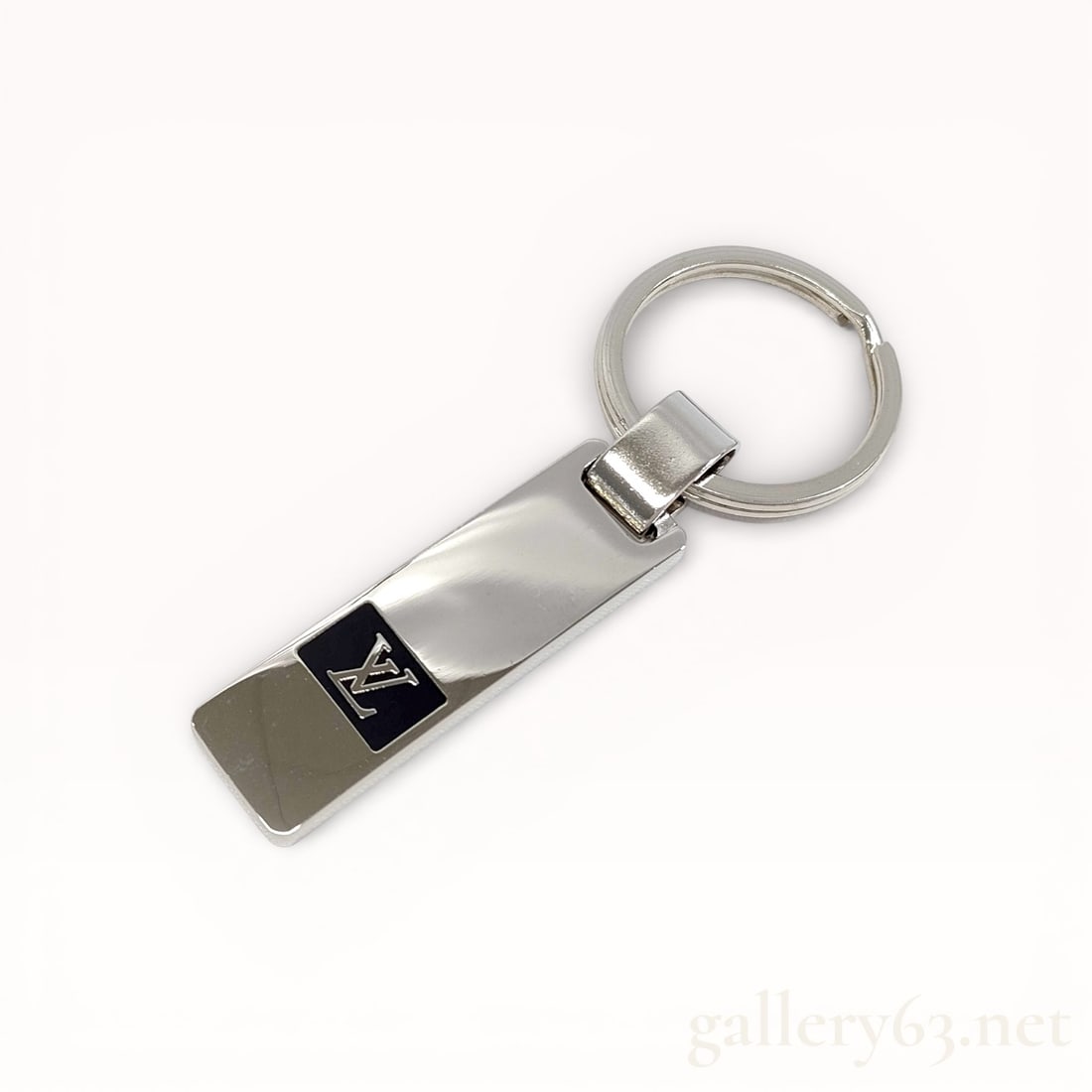 Louis Vuitton Polished Metal Key Ring with Enamel Logo Plaque: Authentic Louis Vuitton key ring executed in polished silver-tone metal, designed with a rectangular bar form and integrated circular split ring. Front featuring a black enamel plaque inset with the L