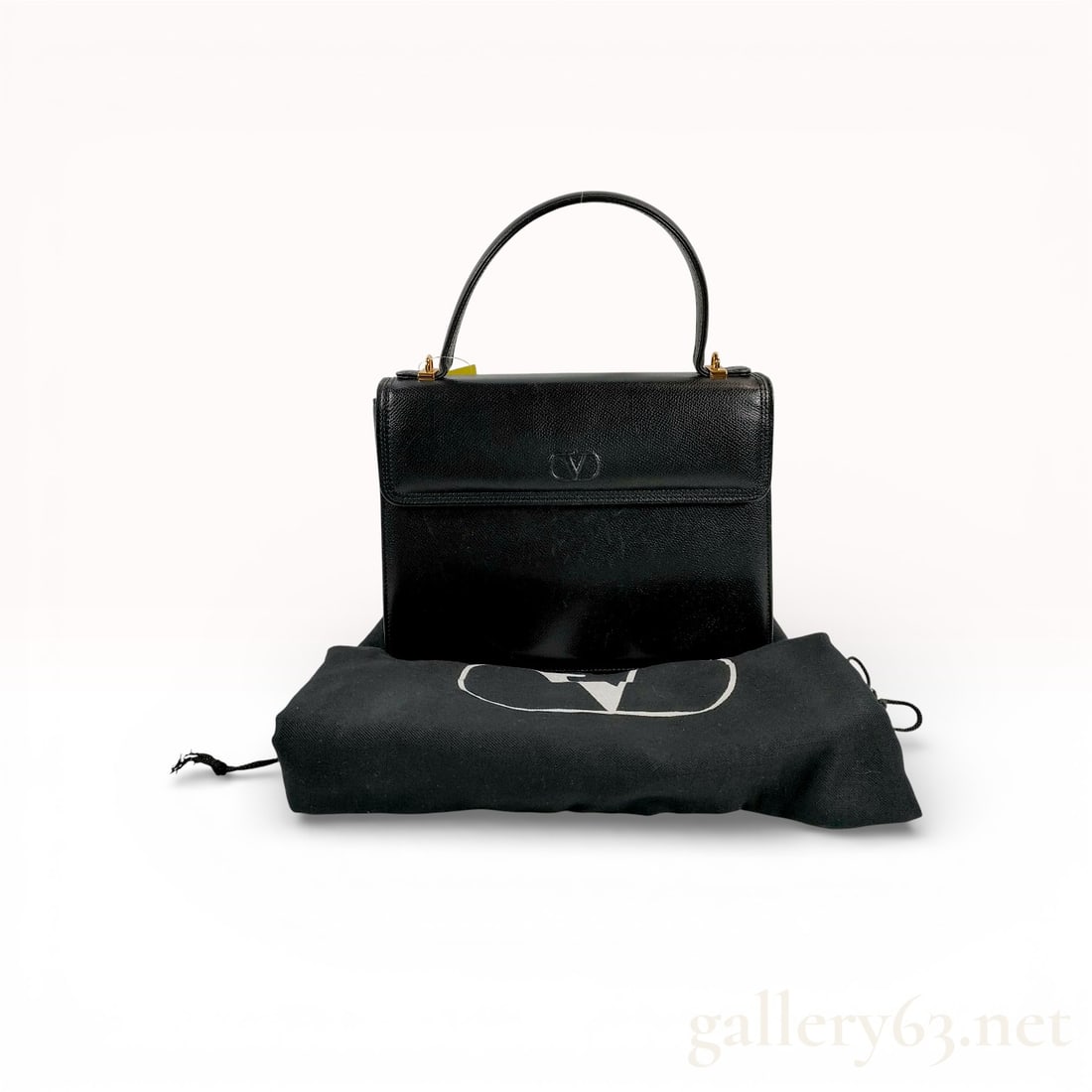 Valentino Garavani Vintage Grained Leather Top Handle Flap Bag Black: This vintage Valentino Garavani top handle handbag is crafted from premium black grained leather in a structured silhouette. The design features a single rounded top handle attached with polished gold