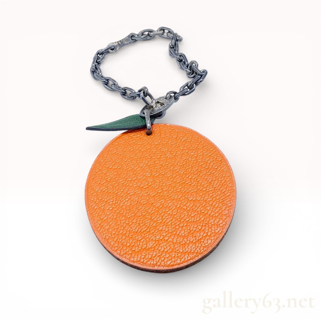 Herm?¨s Orange Fruit Bag Charm, Grained Leather and Sterling Silver: This authentic Herm?¨s bag charm features a circular orange grained leather body representing the fruit, paired with a textured green leather leaf. The leaf is stamped with the HERM??S signature. It