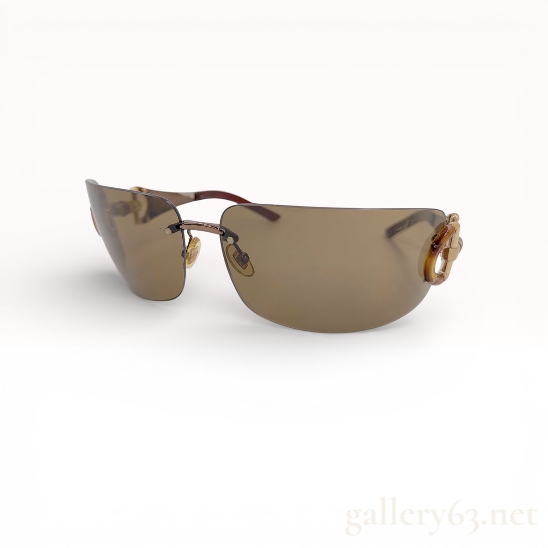 Gucci Rimless Shield Sunglasses, Bamboo Horsebit Tortoiseshell Metal and Plastic: This pair of Gucci rimless shield sunglasses is crafted from metal and plastic. The design features a continuous-look rimless front with a bronze-tone metal bridge and adjustable nose pads. The temple