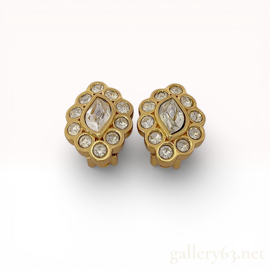 Gold-Toned Christian Dior Crystal Scalloped Clip-On Earrings: A matched pair of vintage Christian Dior clip-on earrings featuring a high-polish gold-toned metal finish. Each earring is designed with a central marquise-cut colorless crystal bezel-set within a sca
