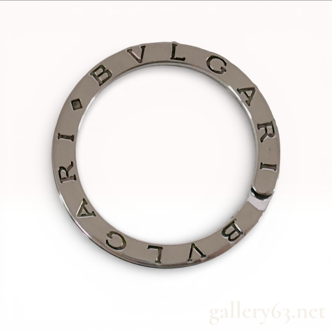 Bvlgari Sterling Silver Key Ring: Bvlgari key ring crafted in 925 sterling silver. The accessory features a flat, circular split-ring design with the BVLGARI brand name engraved twice around the circumference, separated by diamond-sha