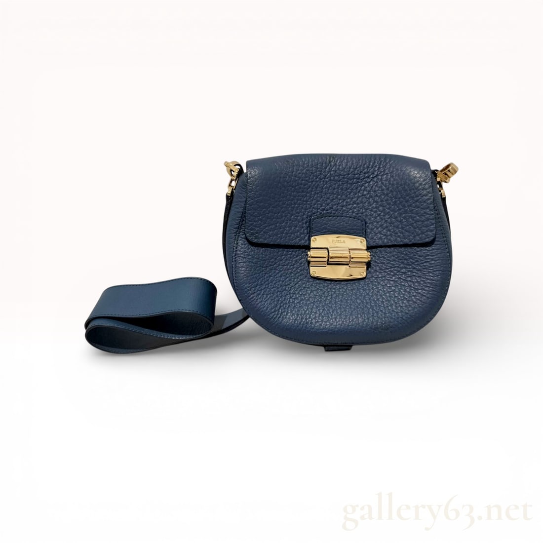 Furla Club Grained Leather Saddle Crossbody Bag, Slate Blue: A Furla Club S crossbody bag crafted from slate blue grained pebbled leather. This rounded saddle-style bag features a flap top with a signature polished gold-tone push-lock clasp engraved with the br