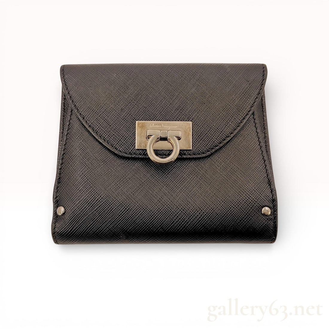 Salvatore Ferragamo Gancini Bifold Wallet Saffiano Leather Black: A classic Salvatore Ferragamo bifold wallet crafted from durable black Saffiano leather. The exterior features a front flap with the iconic Gancini clasp that opens to a gusseted coin compartment. The