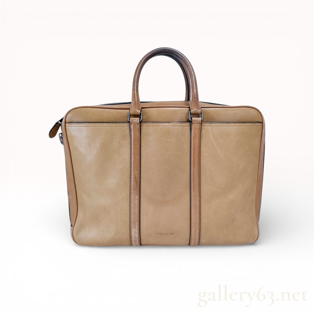 Coach Metropolitan Slim Briefcase, Tan Glove-Tanned Leather: A professional Coach Metropolitan slim briefcase crafted from smooth tan glove-tanned leather with gunmetal-tone hardware. This classic silhouette features dual rolled top handles and a secure zip-top