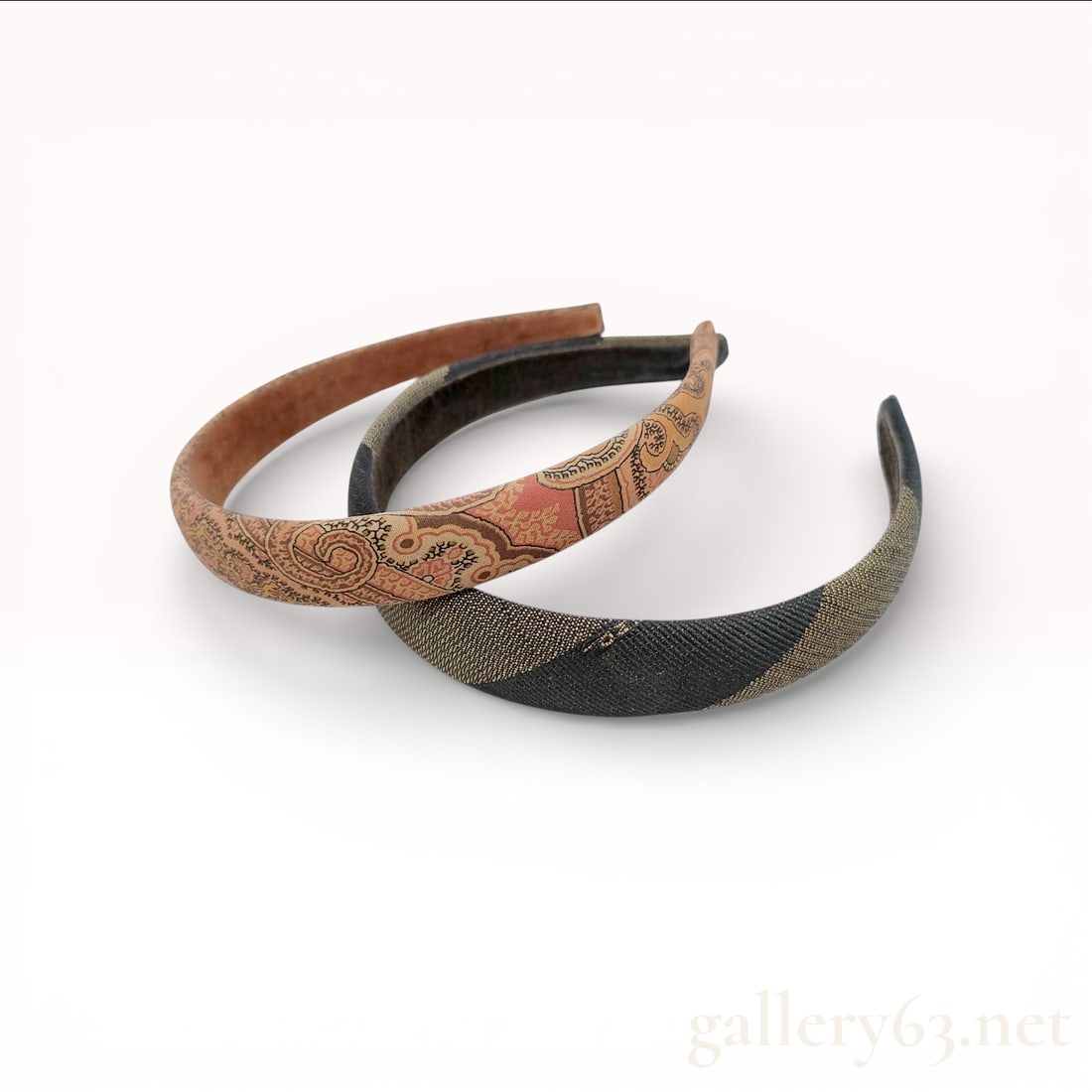 A Pair of Fendi and Paisley Fabric-Covered Headbands: This lot features two fabric-covered hair accessories. The first is a designer headband by Fendi, showcasing a woven exterior in a diagonal stripe pattern in shades of dark brown and gold-toned tan.
