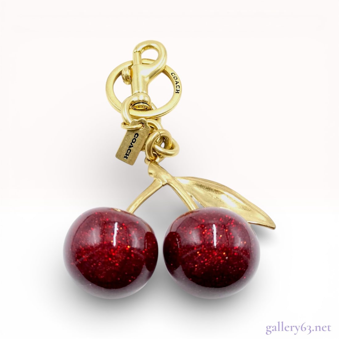 Coach Resin Cherry Bag Charm, Red Glitter and Gold-Tone Metal: This Coach bag charm and keychain features a whimsical cherry design. The piece is composed of two three-dimensional spheres crafted from deep red resin with an integrated glitter finish. The cherries