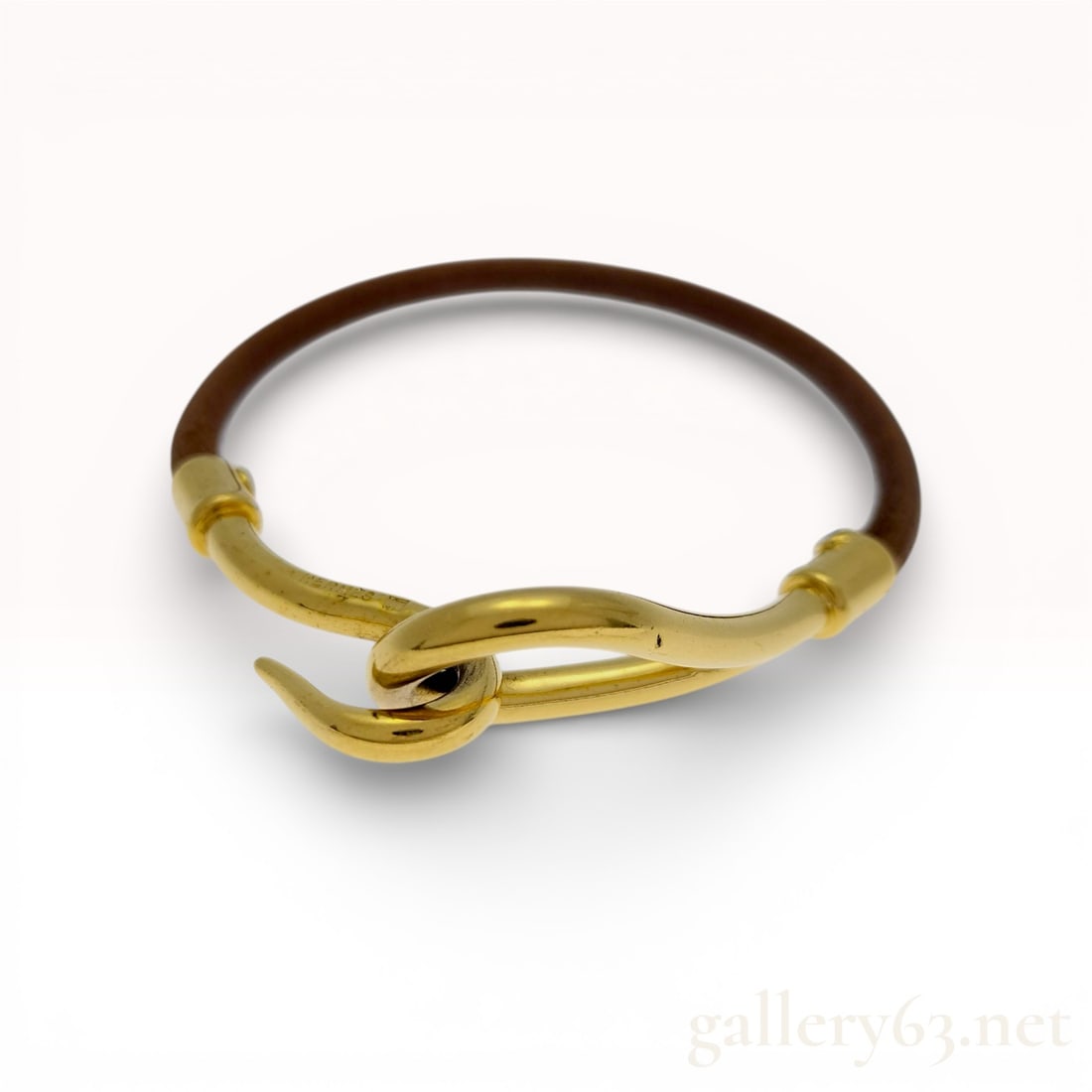 Gold-Plated Hermes Jumbo Hook Leather Bracelet: This Hermes Jumbo Hook bracelet features a supple round brown leather cord. The minimalist design is joined by a signature oversized polished yellow gold-plated metal hook-and-eye clasp. The interior