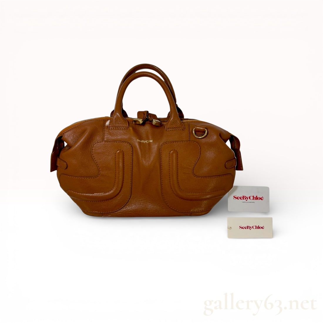 See by Chloé Kay Grained Leather Satchel in Cognac: This See by Chloé Kay satchel is crafted from supple cognac-toned grained leather. The exterior features decorative curved stitched overlays on the front and back panels, dual rolled top handle