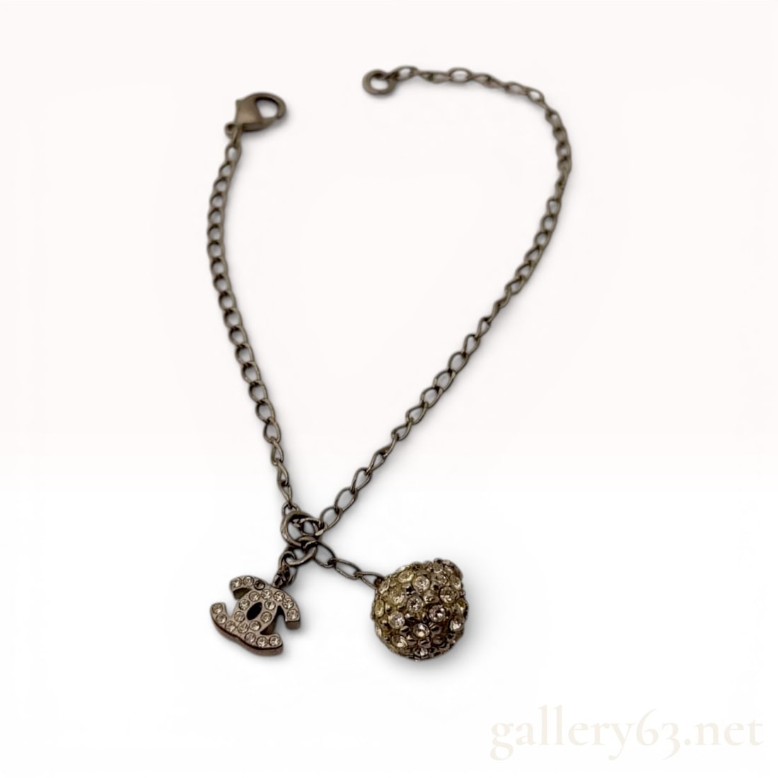 Chanel 2007 Antiqued Silver-Tone Chanel Charm Bracelet with Crystal CC and Spherical Drops: This designer charm bracelet is crafted from antiqued silver-tone base metal with a dark ruthenium-style finish. The piece features a classic link chain supporting two distinct charms: an iconic inter