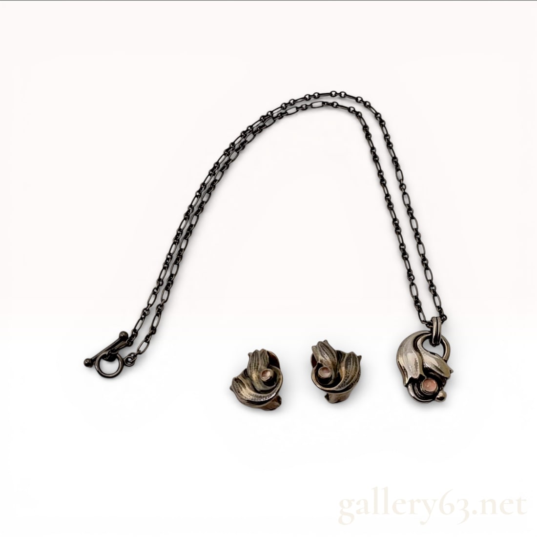 Sterling Silver Pendant Necklace and Earring Suite, Georg Jensen 1999 Heritage: A sterling silver jewelry suite from the Georg Jensen 1999 Heritage collection featuring an Art Nouveau-inspired floral motif with a deliberate oxidized finish. The suite includes a pendant suspended