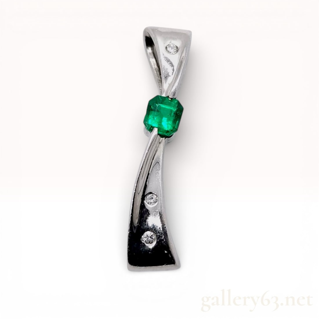 Platinum, Emerald, and Diamond Stylized Ribbon Pendant: A platinum pendant designed as a stylized ribbon or curved bow with an integrated bail. The center of the pendant features one emerald-cut natural emerald, measuring approximately 4mm by 3.5mm, with