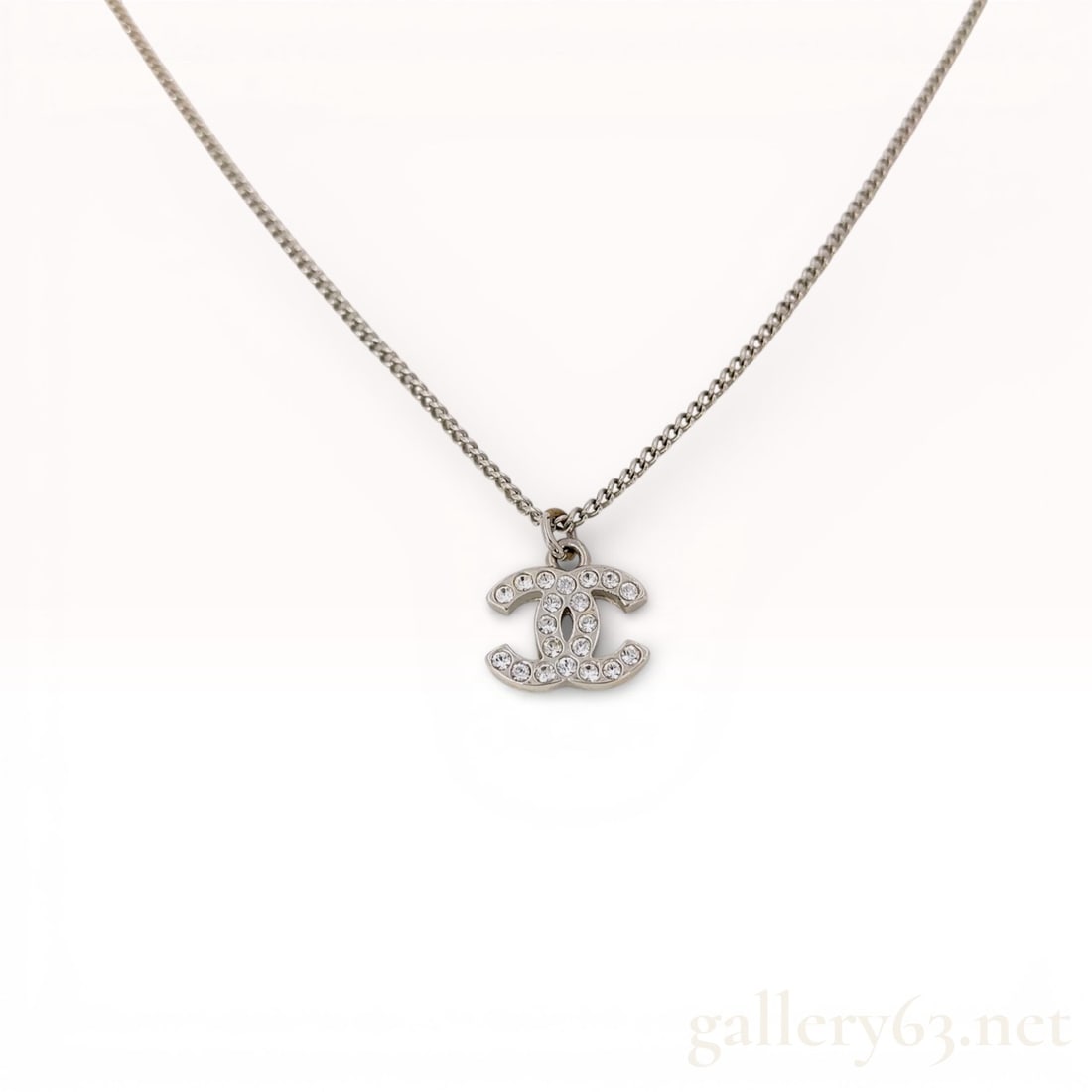 Silver-Tone Curb Link Necklace with Crystal-Set CC Pendant: A Chanel costume jewelry necklace featuring a silver-tone fine curb link chain and a signature interlocking CC logo pendant. The pendant is pavé-set with clear crystals on the front and