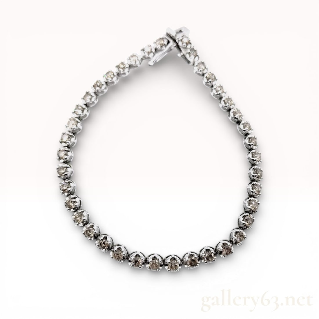 18K White Gold Champagne Diamond Tennis Bracelet: An 18 karat white gold tennis-style link bracelet featuring a continuous row of round brilliant-cut diamonds. The diamonds display a light-to-medium brown champagne hue. The piece is secured with an i