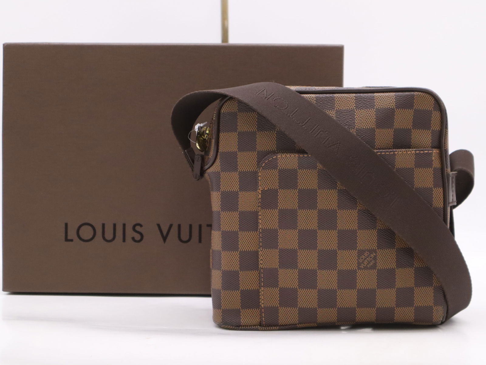 Louis Vuitton Olav PM Messenger Bag Damier Ebene Canvas Brown: This Louis Vuitton Olav PM messenger bag is crafted from signature Damier Ebene coated canvas with dark brown leather trim. The exterior features a front slip pocket and a top zipper closure. It is