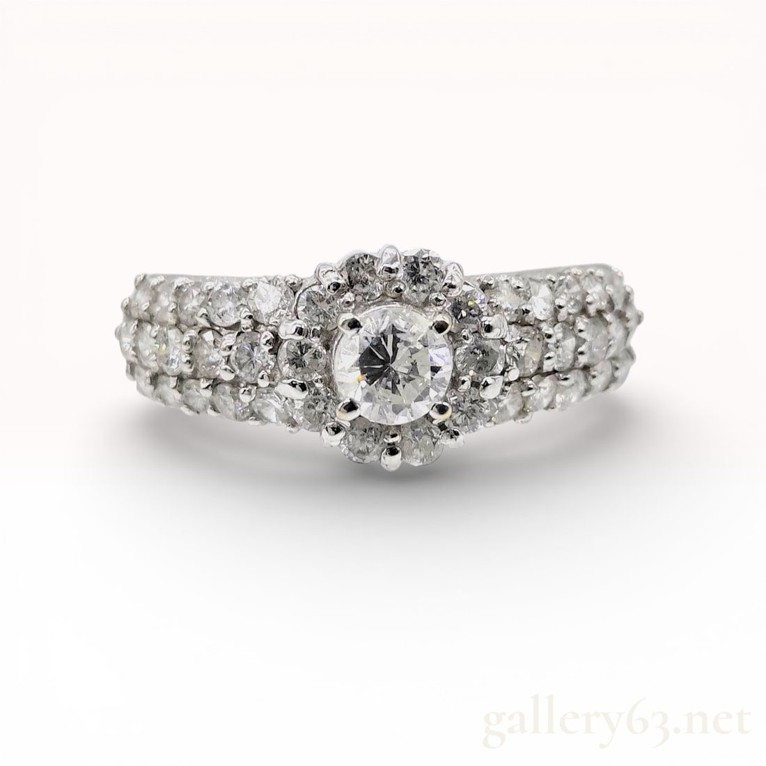 18K White Gold H-SI2-GD-FAINT 1.08ctw Diamond Halo Engagement Ring: This 18 karat white gold ring features a round brilliant-cut diamond center stone secured in a four-prong setting. The center diamond is encircled by a halo of smaller round brilliant-cut diamonds.