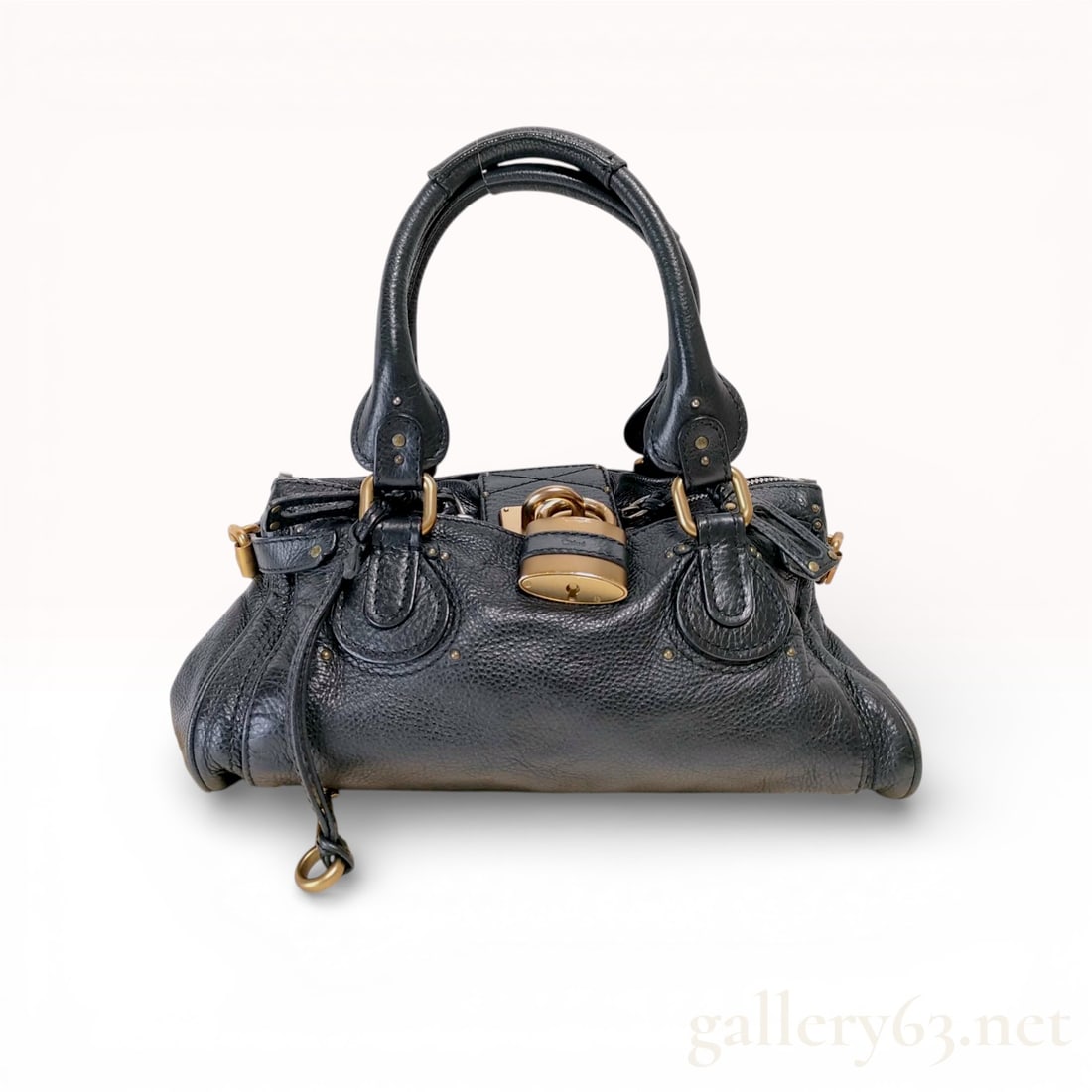 Chloé Paddington Medium Grained Leather Satchel in Black: This Chloé Paddington satchel is a definitive example of mid-2000s luxury design, constructed from heavy-weight, pebbled black calfskin leather. The bag features the iconic oversized antique