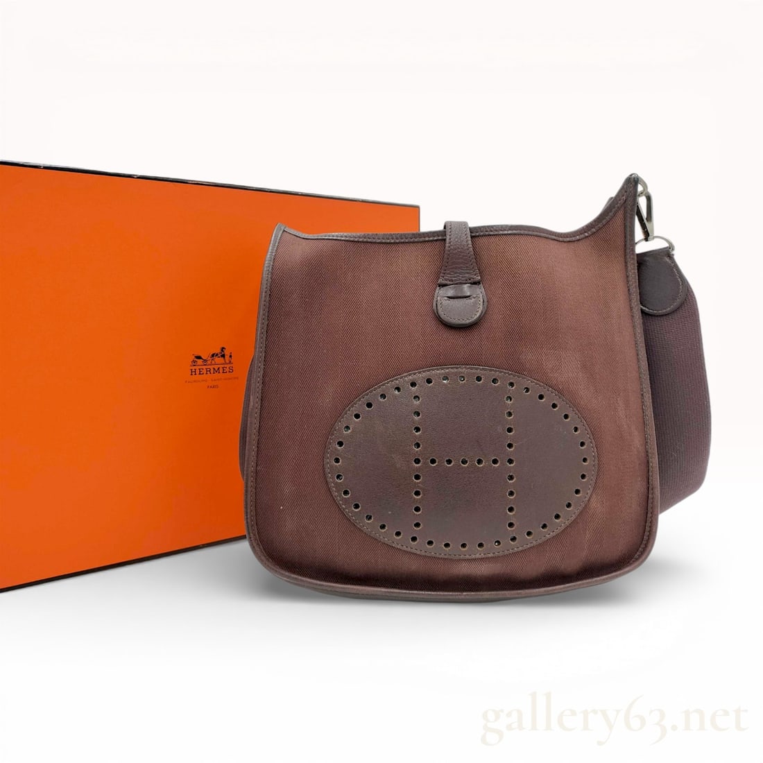 Hermes Evelyne II PM Toile and Leather Crossbody Bag in Ebene: This Hermes Evelyne II PM (size 29) crossbody messenger bag is crafted from dark brown Ebene herringbone Toile canvas with tonal grained leather trim. A signature feature of this model is the large