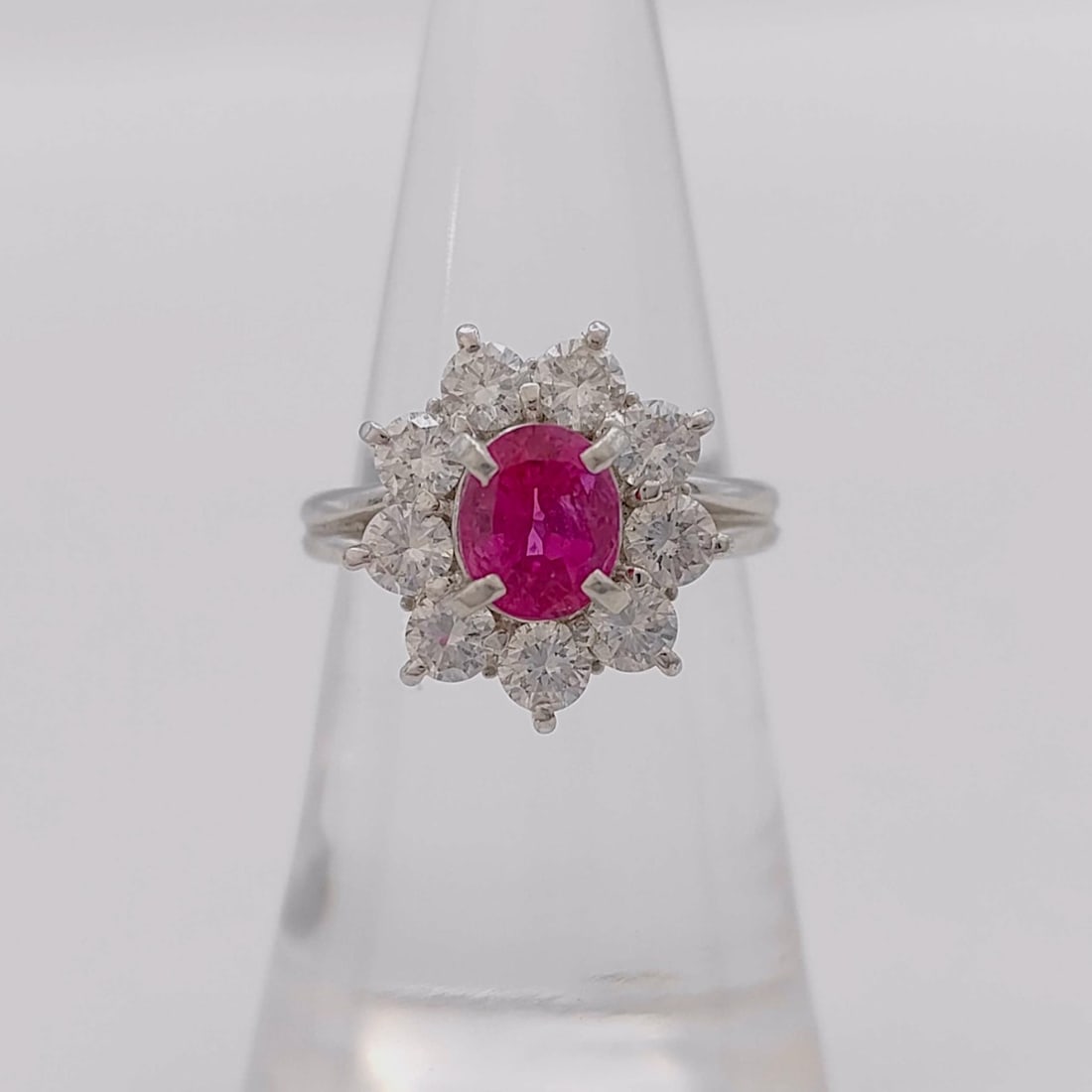 Platinum, Ruby, and Diamond Cluster Ring: A vintage-style cocktail ring crafted in platinum 900. The design features a central oval mixed-cut ruby, approximately 1.71 carats, exhibiting a vibrant pinkish-red color with natural internal charac