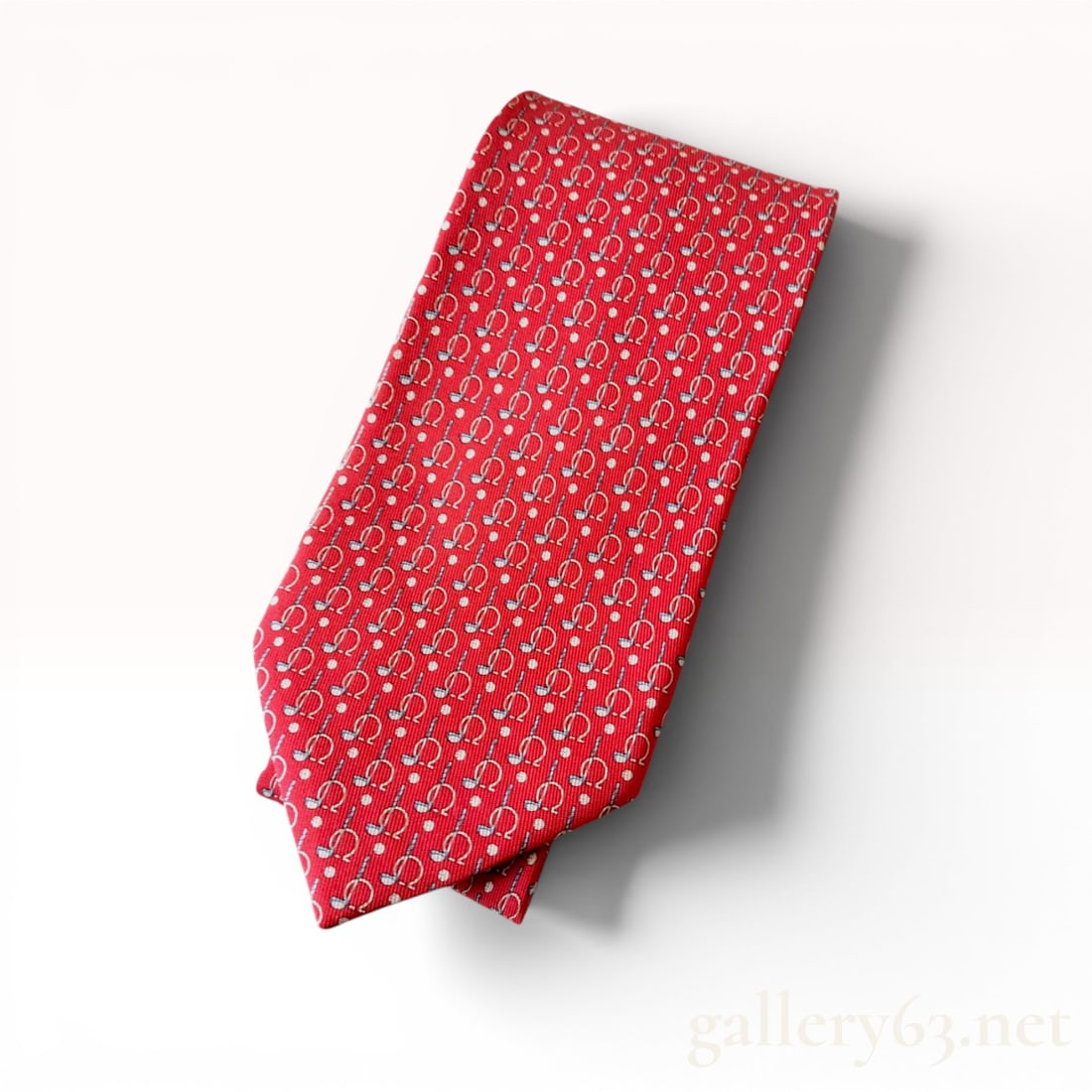 Salvatore Ferragamo Red Silk Golf Print Gancini Necktie: Salvatore Ferragamo silk necktie, modern. Red silk ground featuring a repeating novelty print of golf clubs and balls accented by Gancini motifs. Reverse features burgundy silk tipping with repeating