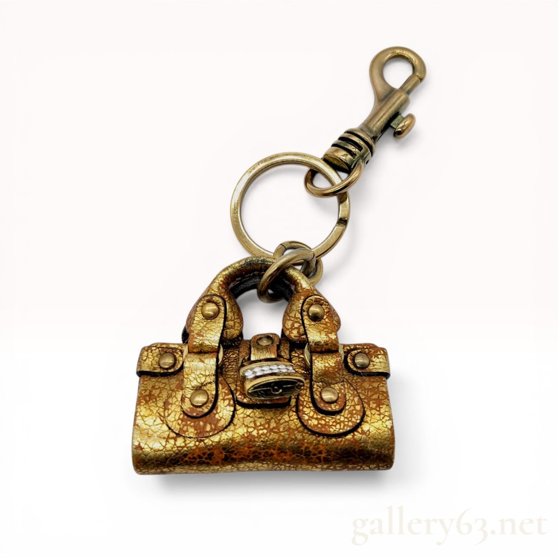 Chloe Paddington Bag Keychain in Metallic Gold Leather: Chloe bag charm designed as a miniature Paddington handbag, early 21st century. It is crafted from metallic gold leather with a distressed finish and features a crystal-encrusted miniature padlock, tw