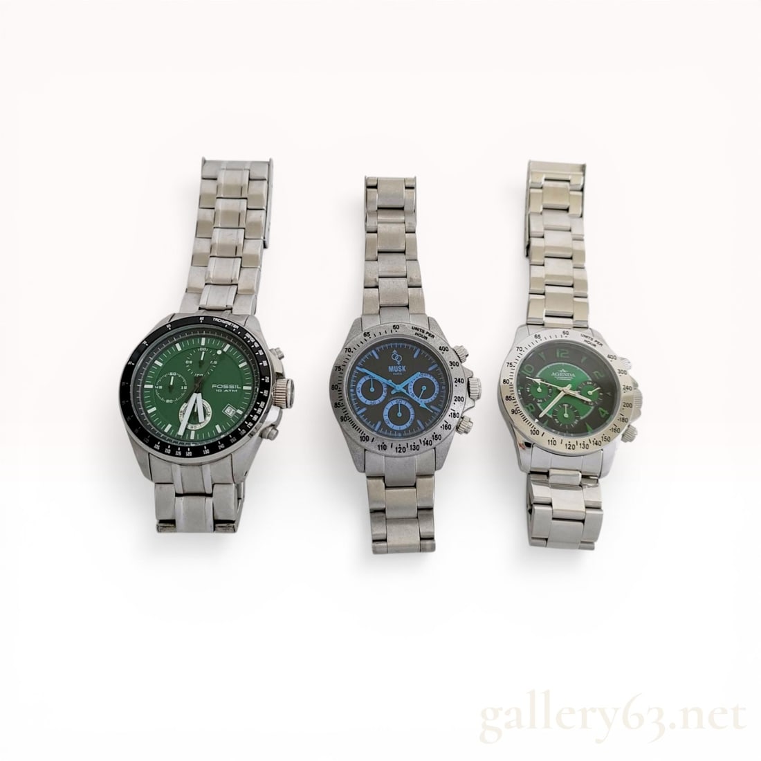 A Trio of Men's Stainless Steel Chronograph Wristwatches Including Fossil, Musk Paris, and Agenda: This lot consists of three men's chronograph-style wristwatches featuring stainless steel construction and link bracelets. The first item is a Fossil Autocross multifunction watch with a green dial, t