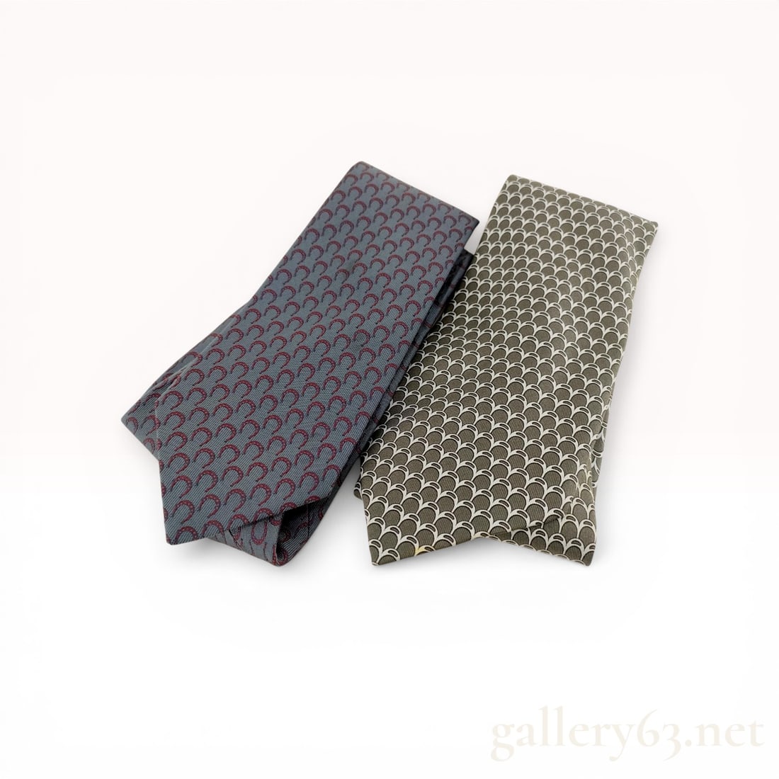 Two Herm?¨s Silk Neckties: Two Herm?¨s 100% silk neckties, manufactured in France. The first tie features a blue-gray ground with a repeating burgundy horseshoe pattern and tone-on-tone H logo tipping; the second tie features