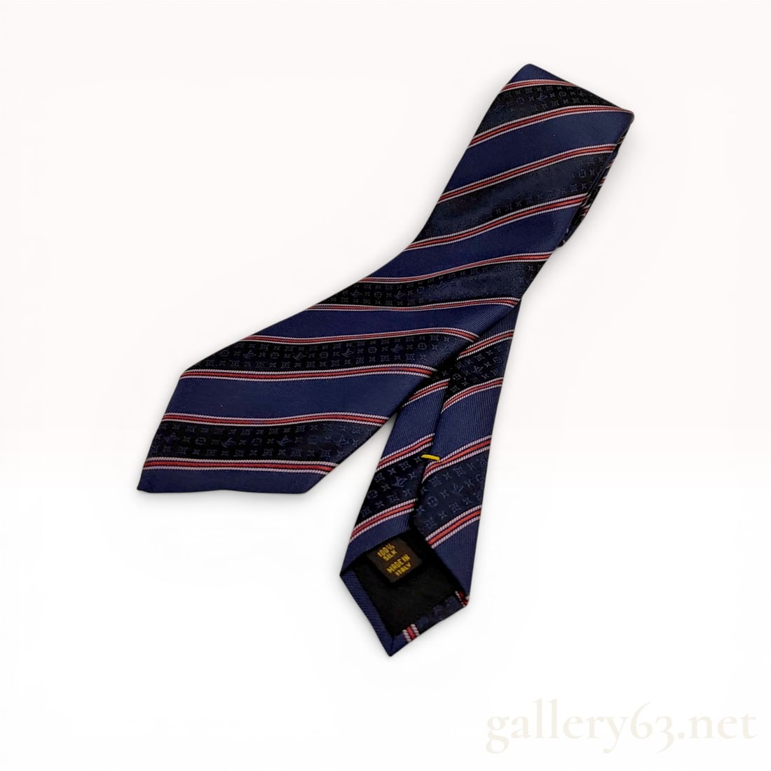 Louis Vuitton Navy Blue Monogram Jacquard Striped Silk Necktie: Louis Vuitton silk necktie featuring a navy blue ground with diagonal red and white stripes. The fabric is constructed from 100 percent silk with a tonal jacquard monogram pattern throughout the navy