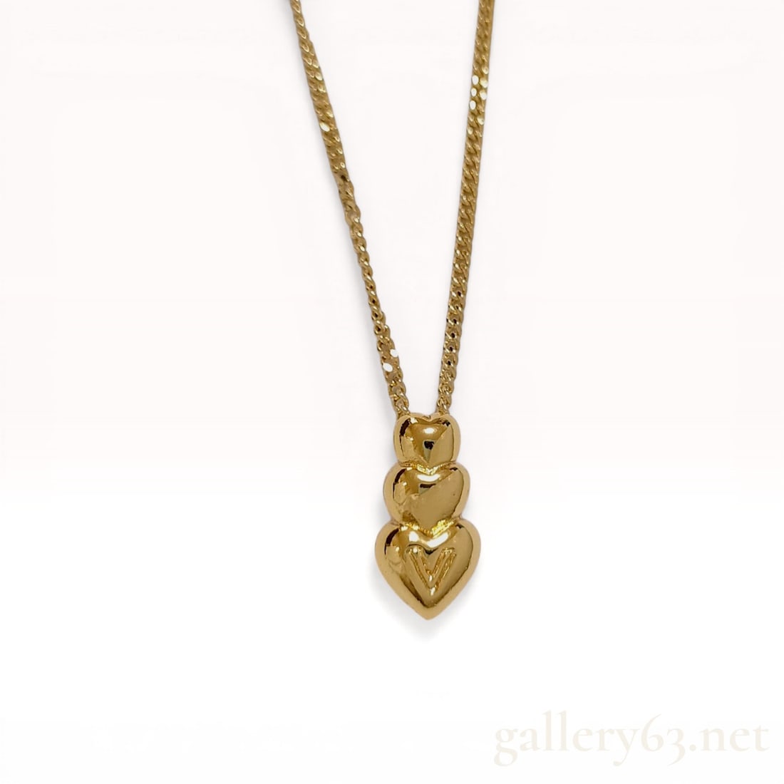 Valentino Gold-Tone Triple Heart Pendant Necklace: Valentino fashion necklace featuring a triple-stacked heart pendant in a polished yellow gold-tone finish. The pendant consists of three vertically arranged hearts of increasing size, with the largest