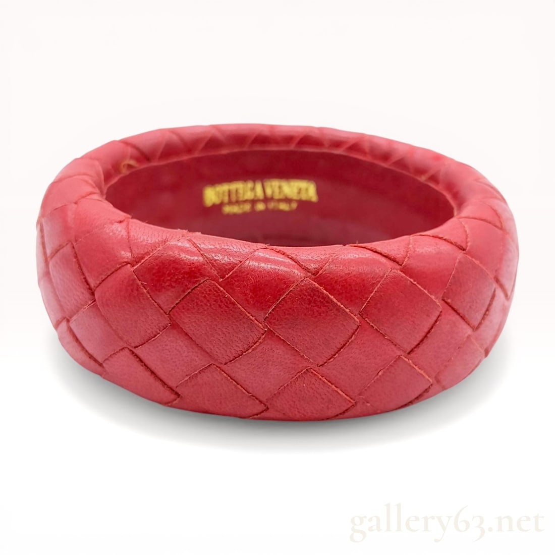 Bottega Veneta Intrecciato Woven Leather Bangle: Bottega Veneta Intrecciato woven leather bangle, contemporary. The accessory is crafted from red leather featuring the signature hand-woven pattern and a smooth tonal leather interior lining. A gold-t