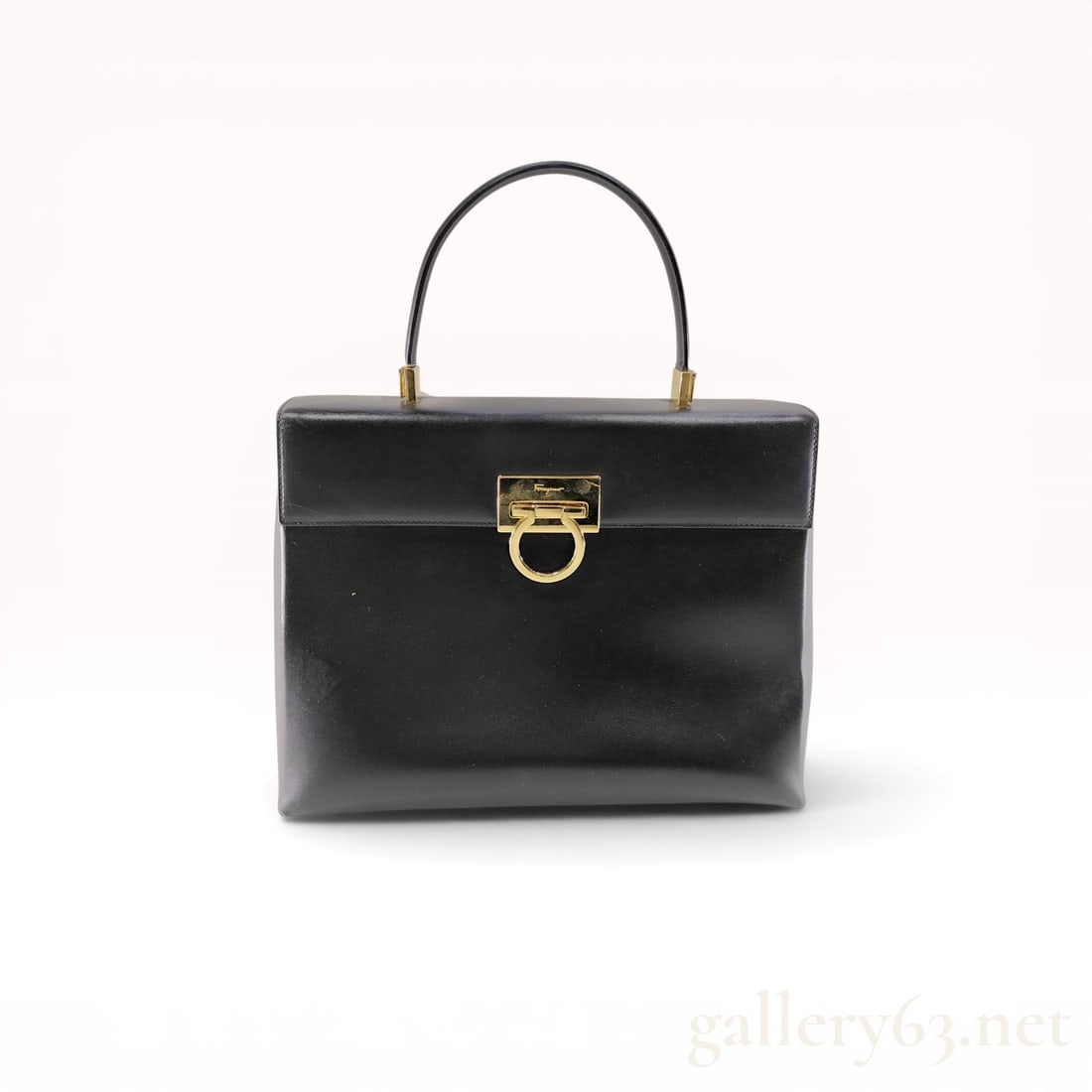 Salvatore Ferragamo Vintage Gancini Top Handle Handbag: Salvatore Ferragamo vintage Gancini top handle handbag, late 20th century. Structured smooth black leather construction featuring a signature gold-toned Gancini flip-lock closure and single rolled han