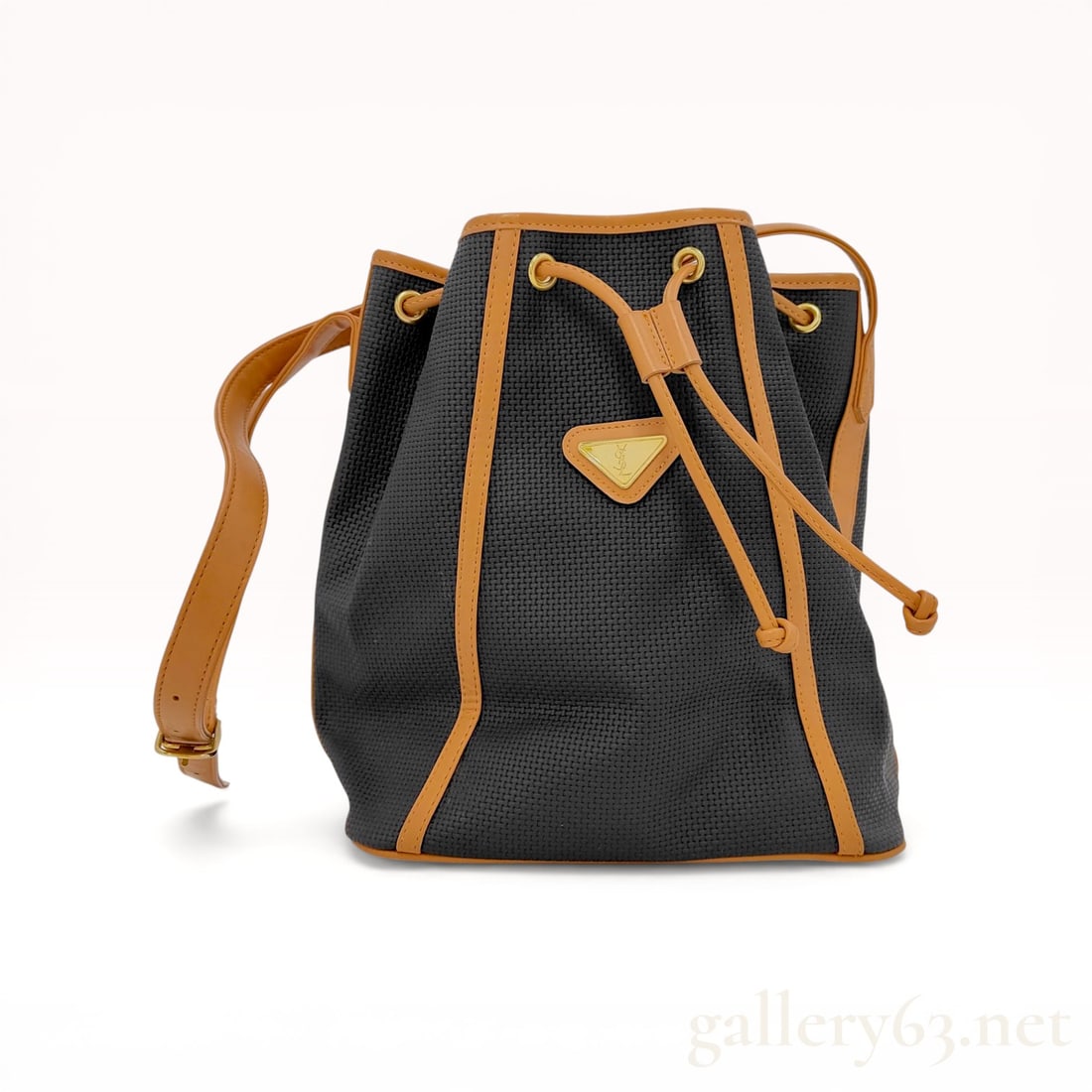 Yves Saint Laurent Vintage Woven Textile and Leather Bucket Bag: Yves Saint Laurent vintage bucket bag, late 20th century. The bag features a black basket-weave textile body accented by tan leather trim, an adjustable shoulder strap, and a drawstring closure. It is