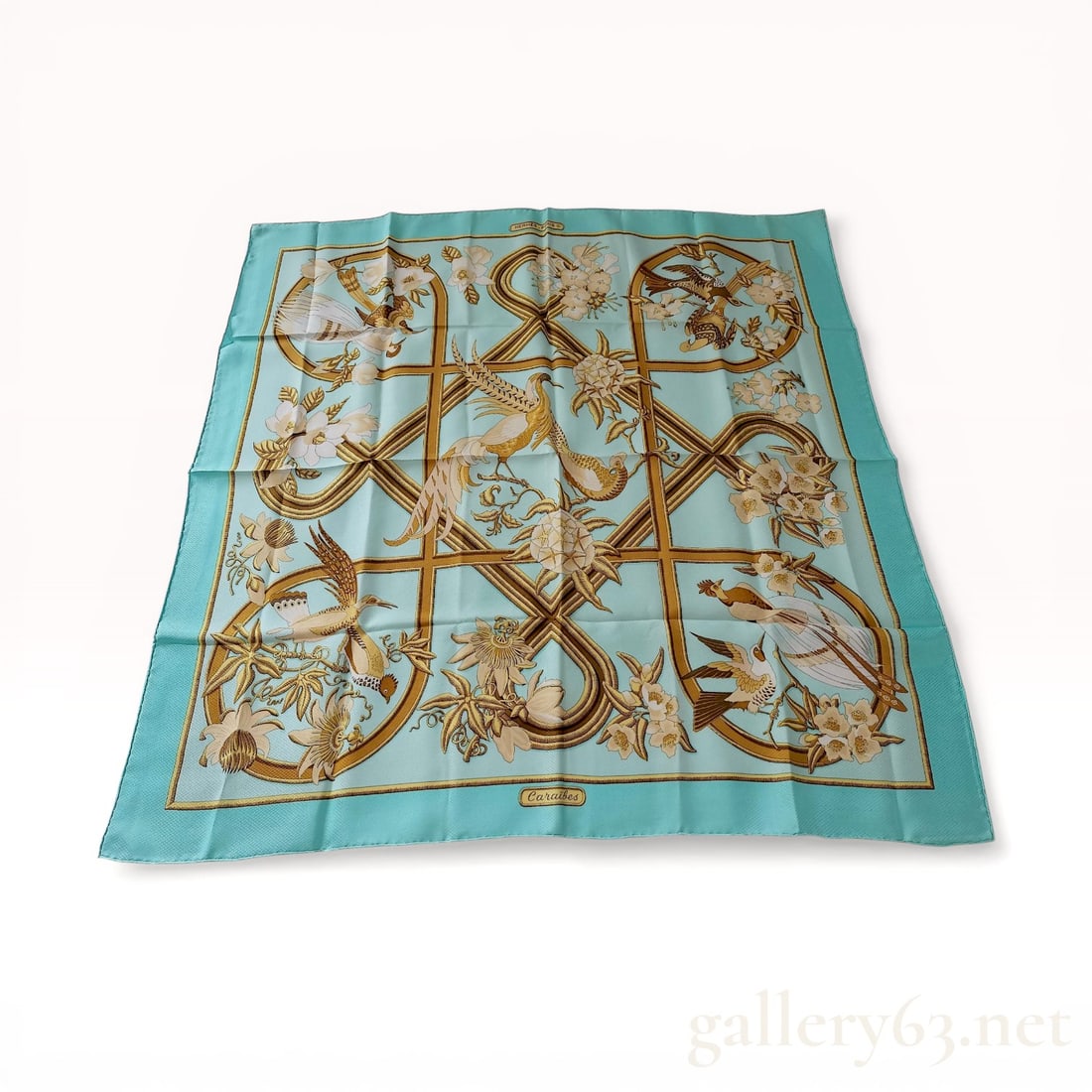 Hermes Caraibes Silk Jacquard Scarf: Hermes silk scarf in the Caraibes pattern, designed by Christiane Vauzelles and featuring a diamond jacquard weave. The turquoise field displays a tropical scene of birds of paradise and passion flowe
