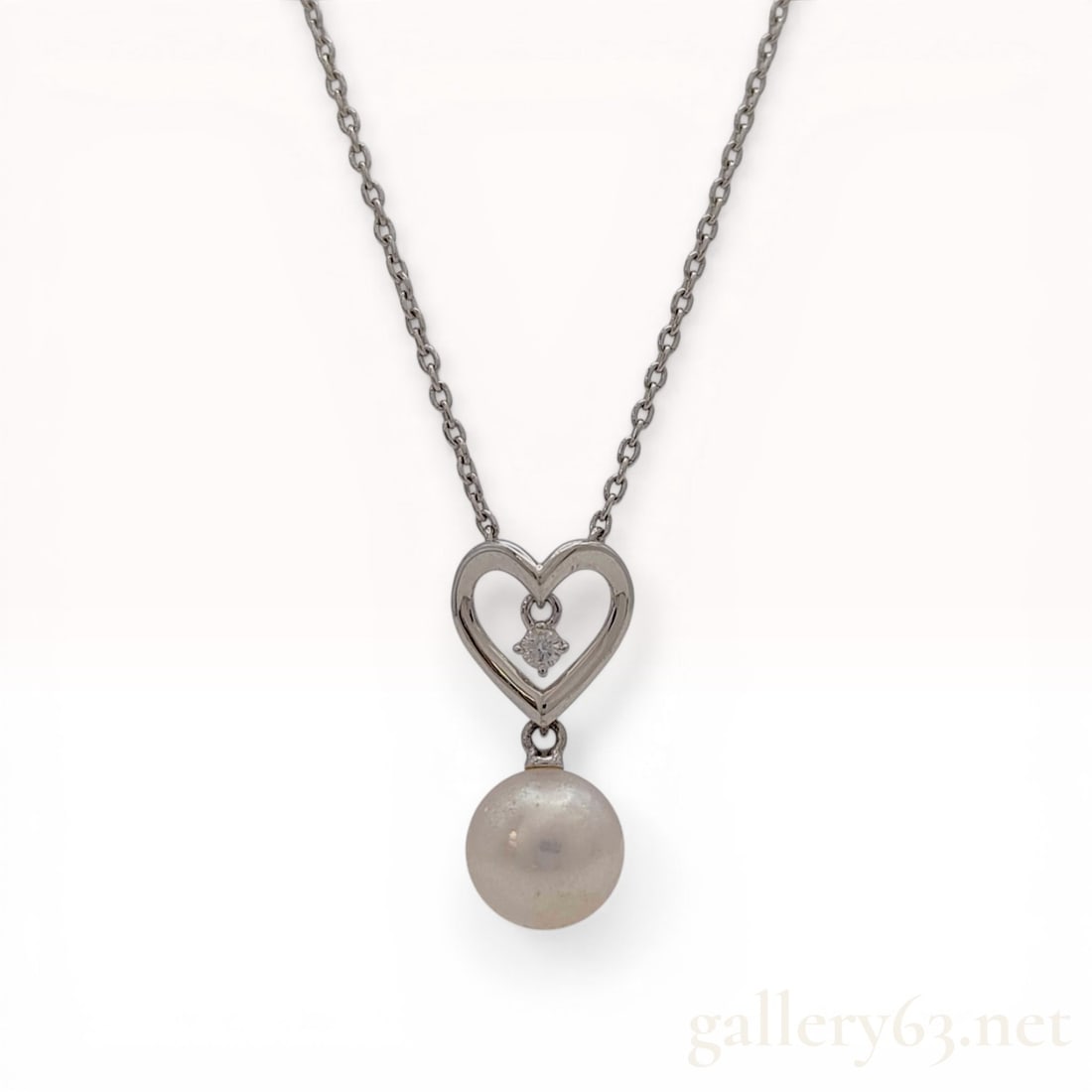 Mikimoto 18 Karat White Gold Pearl and Diamond Heart Pendant Necklace: Mikimoto pendant necklace featuring a heart-shaped motif in 18 karat white gold. The open-work heart frame suspends a single round brilliant-cut diamond in a four-prong mount, with a round cultured