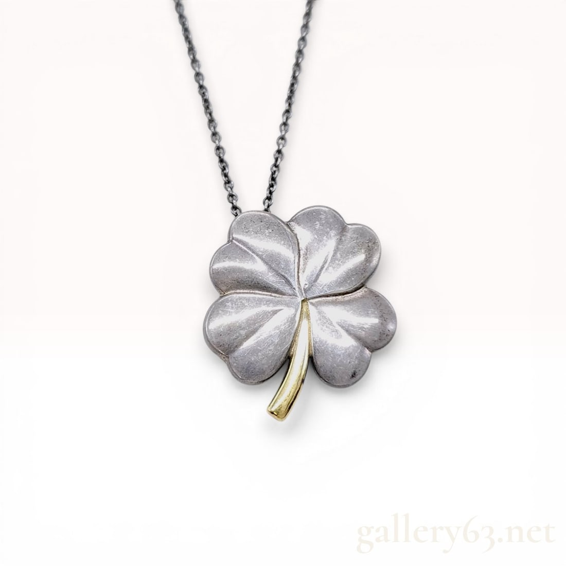 Tiffany and Co. Sterling Silver and 18 Karat Yellow Gold Four-Leaf Clover Pendant Necklace: Tiffany and Co. four-leaf clover pendant necklace crafted in sterling silver and 18 karat yellow gold. The stylized pendant features a three-dimensional clover design with a contrasting yellow gold st