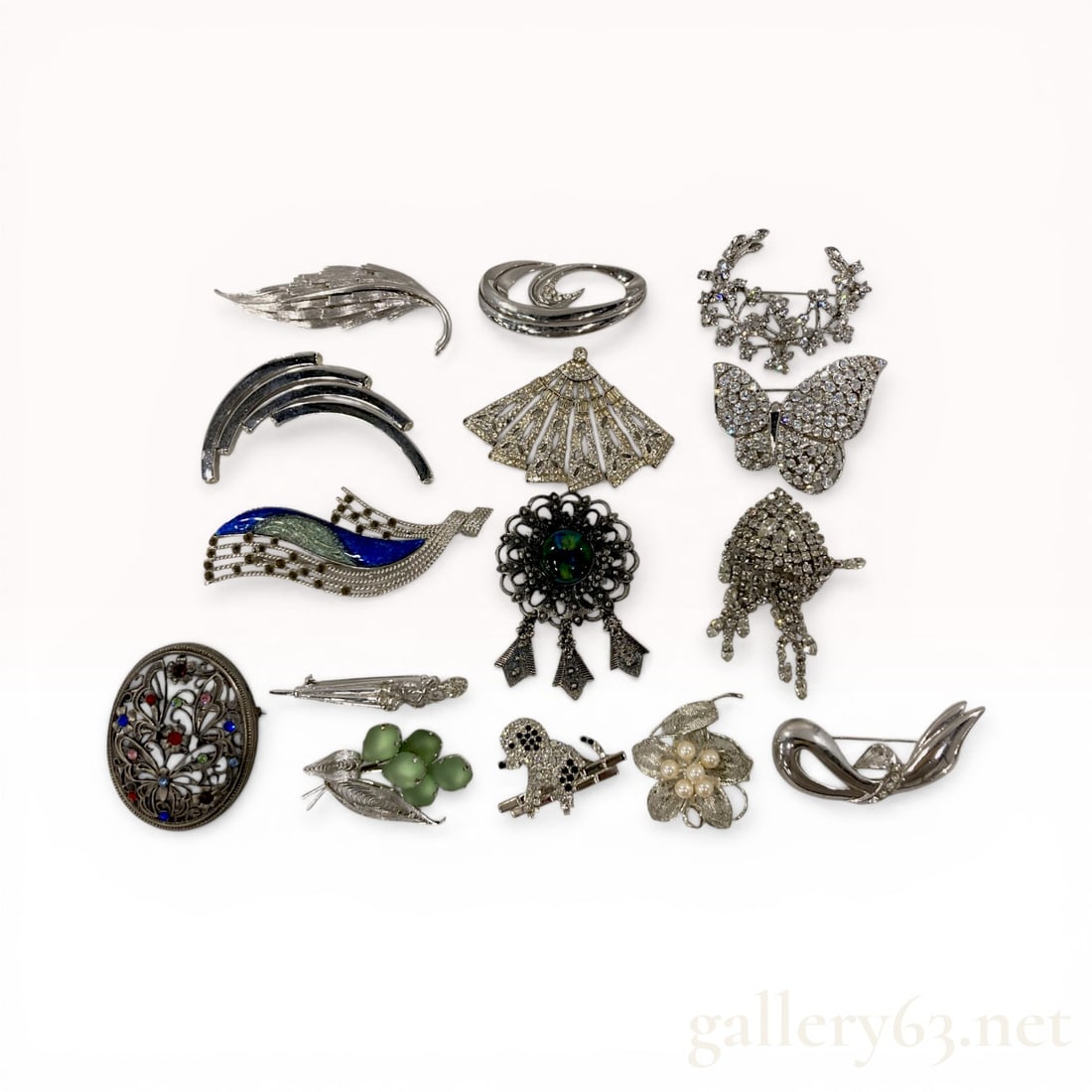 A Collection of Fifteen Costume Jewelry Brooches Including Butler and Wilson: A collection of fifteen costume jewelry brooches featuring animal, floral, and modernist motifs. The group includes a silver-tone poodle brooch marked Butler and Wilson encrusted with clear and black