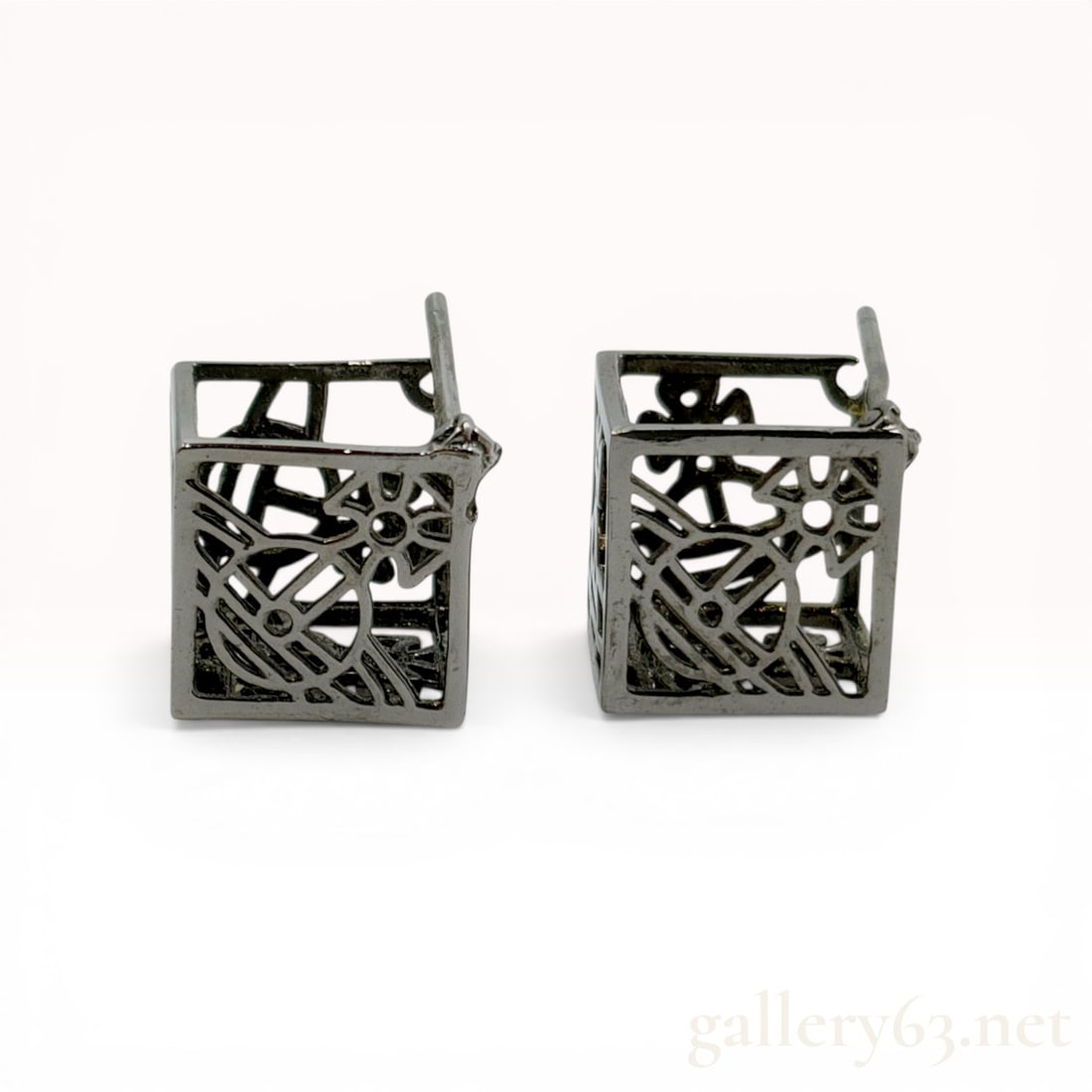 A Pair of Vivienne Westwood Gunmetal-Tone Cube Stud Earrings with Orb Motif: A matched pair of contemporary stud earrings in gunmetal-tone metal, featuring a hollow open-work cube design. Each face of the cube displays an integrated globus cruciger orb motif, queen Vivienne We