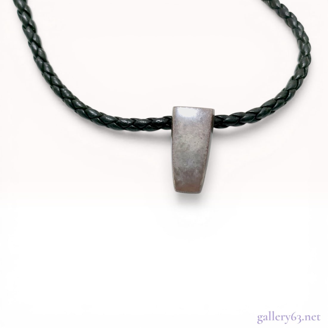 Georg Jensen Sterling Silver Pendant Necklace Design 423: Georg Jensen sterling silver pendant necklace, design number 423, circa 2006. The minimalist wedge-shaped pendant is suspended from a black braided leather cord featuring a cylindrical interlocking st