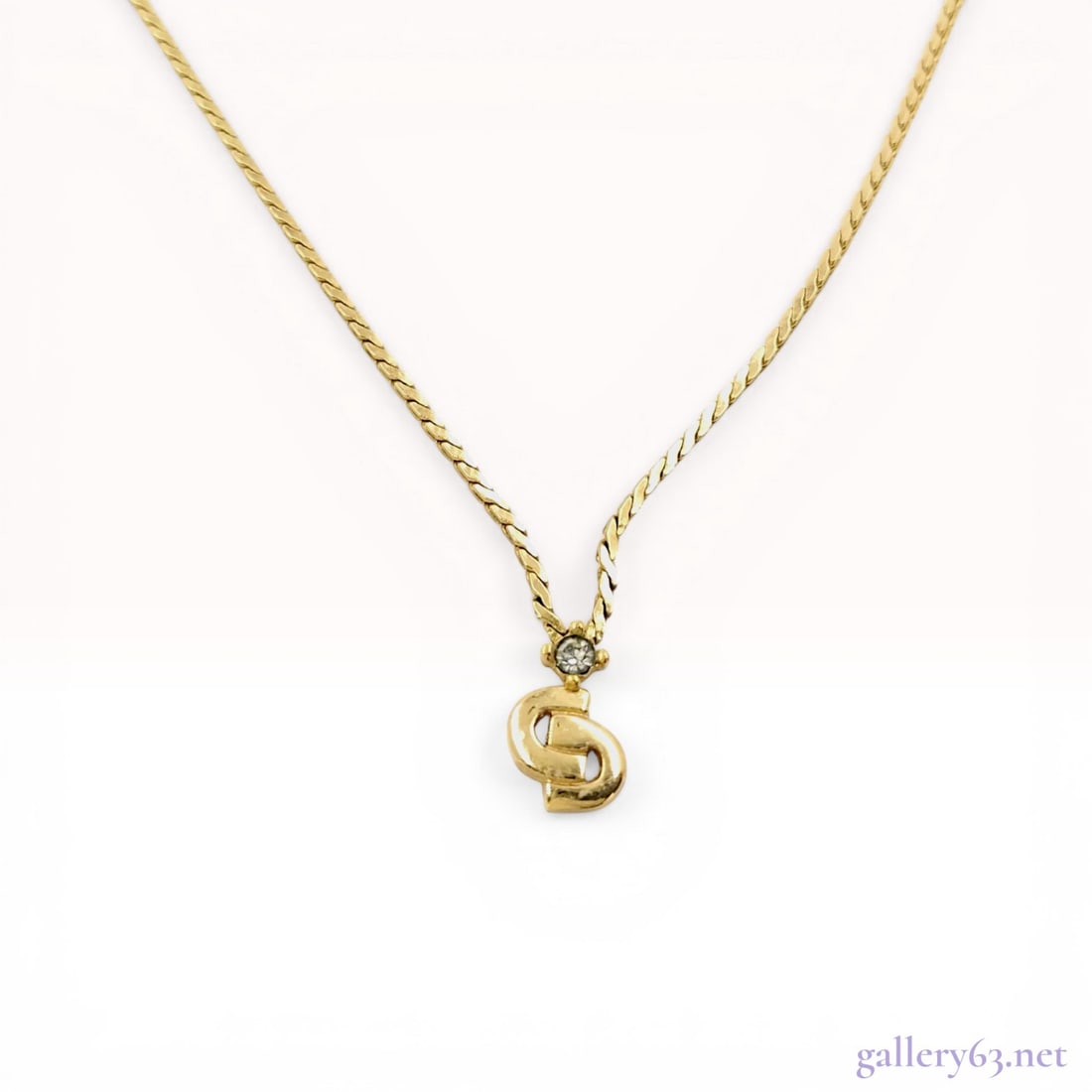 Christian Dior CD Logo Gold Tone Rhinestone Necklace: Christian Dior gold-tone necklace featuring a stylized CD logo pendant, manufactured in Germany. The pendant is suspended from a single clear round-cut rhinestone set in a four-prong mount. The piece