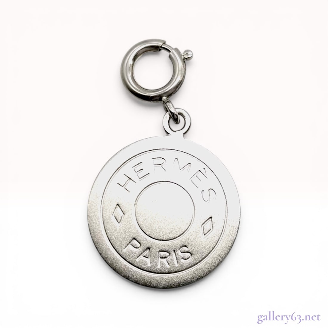 Hermes Clou de Selle Medallion Pendant Charm: Hermes Clou de Selle medallion pendant charm from the Bijouterie Fantaisie collection. The circular silver-tone metal medallion features a concentric Sellier design with a textured outer ring and is s