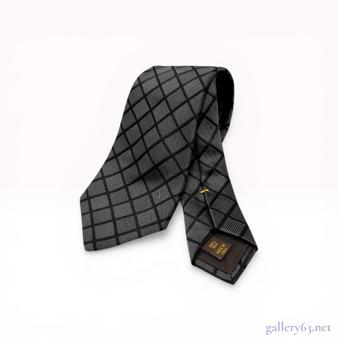 Louis Vuitton Silk Geometric Diamond Grid Pattern Necktie: Louis Vuitton silk necktie featuring a woven dark grey and black geometric diamond grid pattern. The 100% silk construction includes a subtle tone-on-tone interlaced LV logo near the blade tip and a s