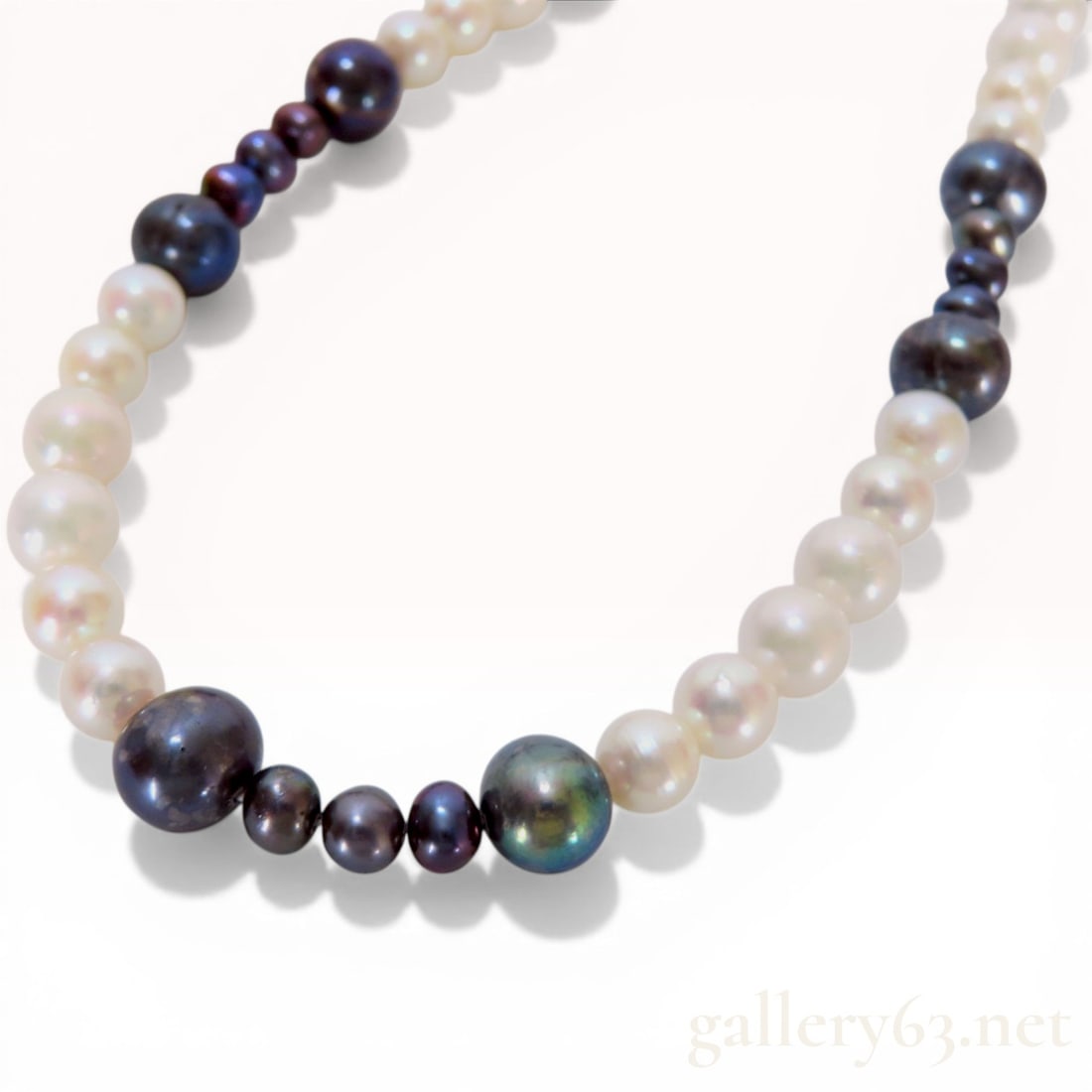 Graduated Multi-Color Cultured Pearl Opera Length Necklace: A continuous strand of graduated cultured pearls featuring alternating sections of cream-white and dark iridescent peacock tones. The pearls vary in shape from near-round to oval and are secured with