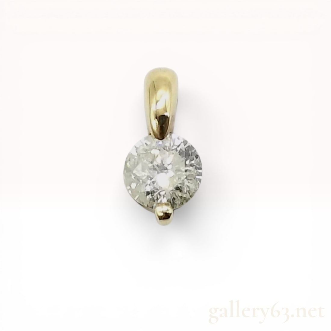 Diamond Solitaire Pendant in 18 Karat Yellow Gold: Diamond solitaire pendant in 18 karat yellow gold. The round brilliant cut diamond is held in a specialized two-point setting with an integrated, wide, polished bail. The reverse of the mounting is st
