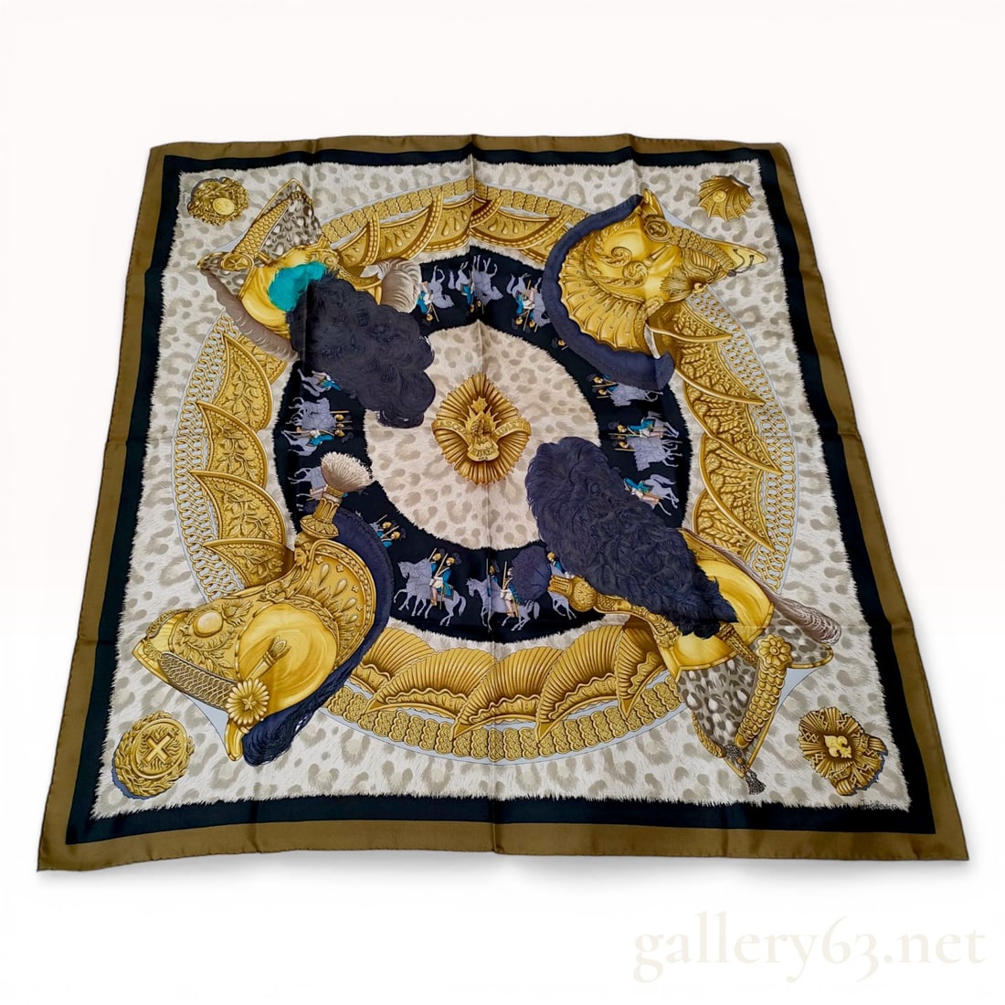 Herm?¨s Casques et Plumets Silk Scarf by Julia Abadie: Hermès silk twill scarf in the Casques et Plumets pattern designed by Julia Abadie, late 20th century. The design features four ornate gold helmets with large plumes surrounding a central sunbu