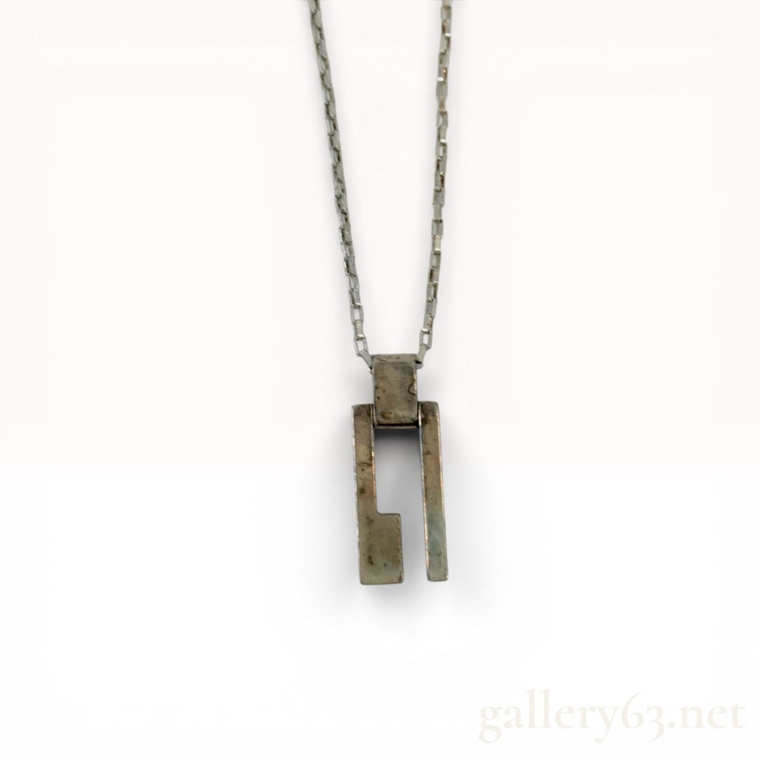 Gucci Sterling Silver Modernist G Pendant Necklace: Gucci modernist pendant necklace featuring a geometric open-work pendant in the form of a stylized letter G. The pendant is suspended from a square box link chain finished with a lobster claw clasp an