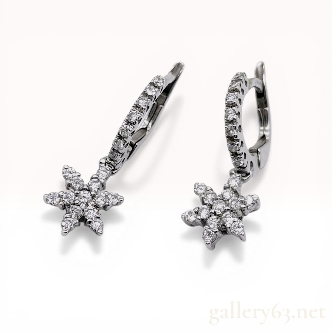 A Pair of 18K White Gold and Diamond Snowflake Huggie Drop Earrings: A matched pair of 18-karat white gold huggie-hoop drop earrings featuring a snowflake motif. Each earring consists of a small hoop set with a row of round brilliant-cut diamonds, suspending a fixed si