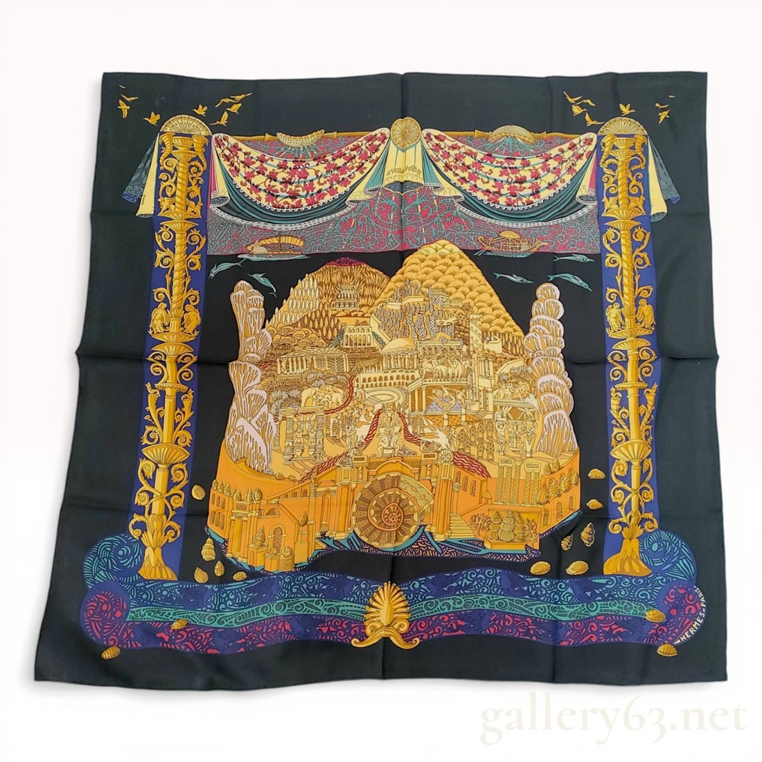 Hermes L'Atlantide Silk Carre 90 Scarf by Annie Faivre: Hermes silk twill scarf featuring the L'Atlantide pattern designed by Annie Faivre, first issued in 1995. The design depicts the mythical city of Atlantis in golden architectural tones centered betwee