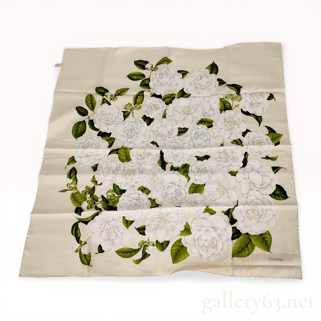 Chanel Silk Camellia Print Square Scarf: Chanel square silk scarf featuring a large central cluster of white camellias with green foliage on a cream ground. The foulard is constructed with hand-rolled and stitched hems and includes a printed