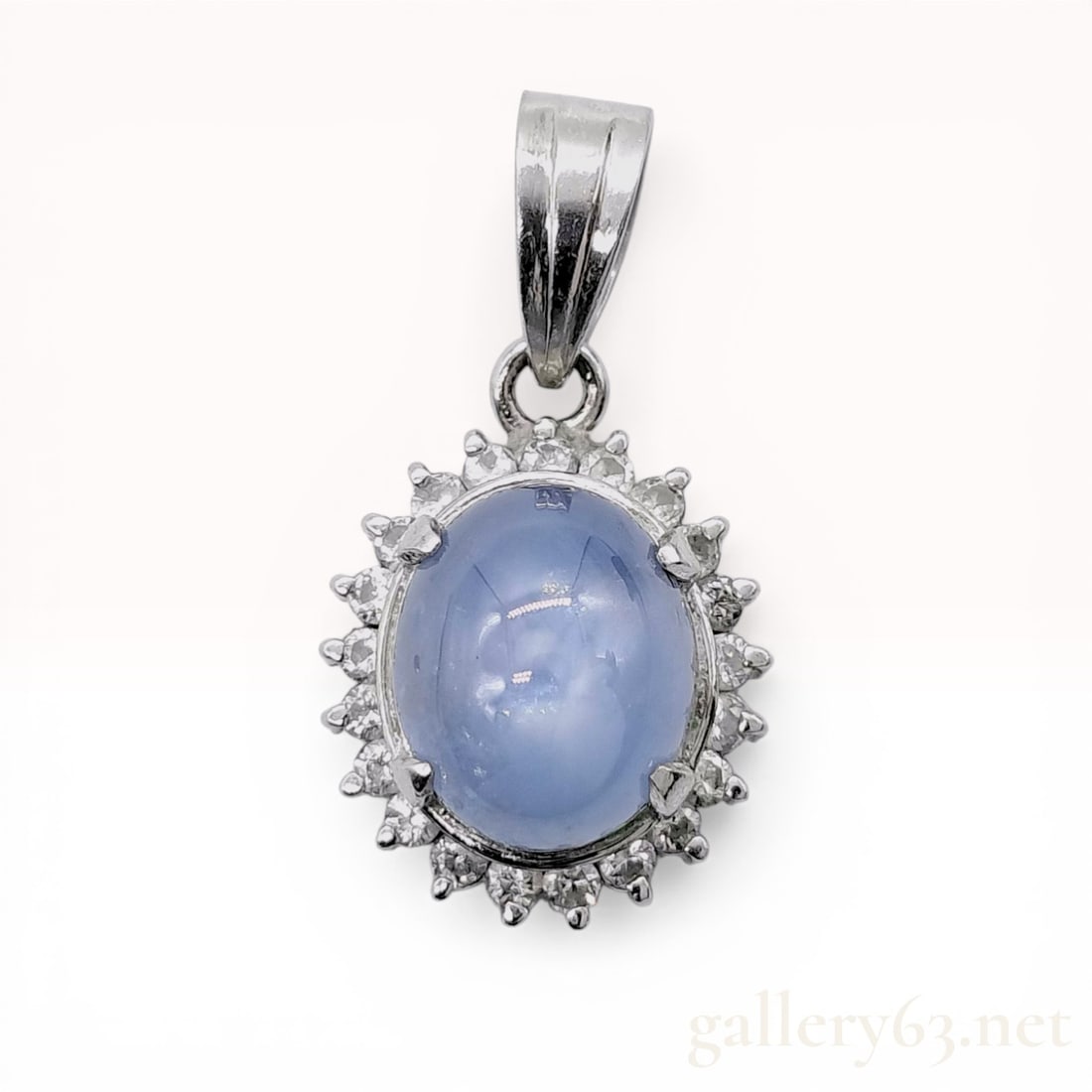 Platinum Star Sapphire and Diamond Halo Pendant: Platinum halo pendant featuring a central oval cabochon star sapphire surrounded by eighteen round brilliant-cut diamonds. The light-blue sapphire displays a six-rayed asterism and is secured in a fou
