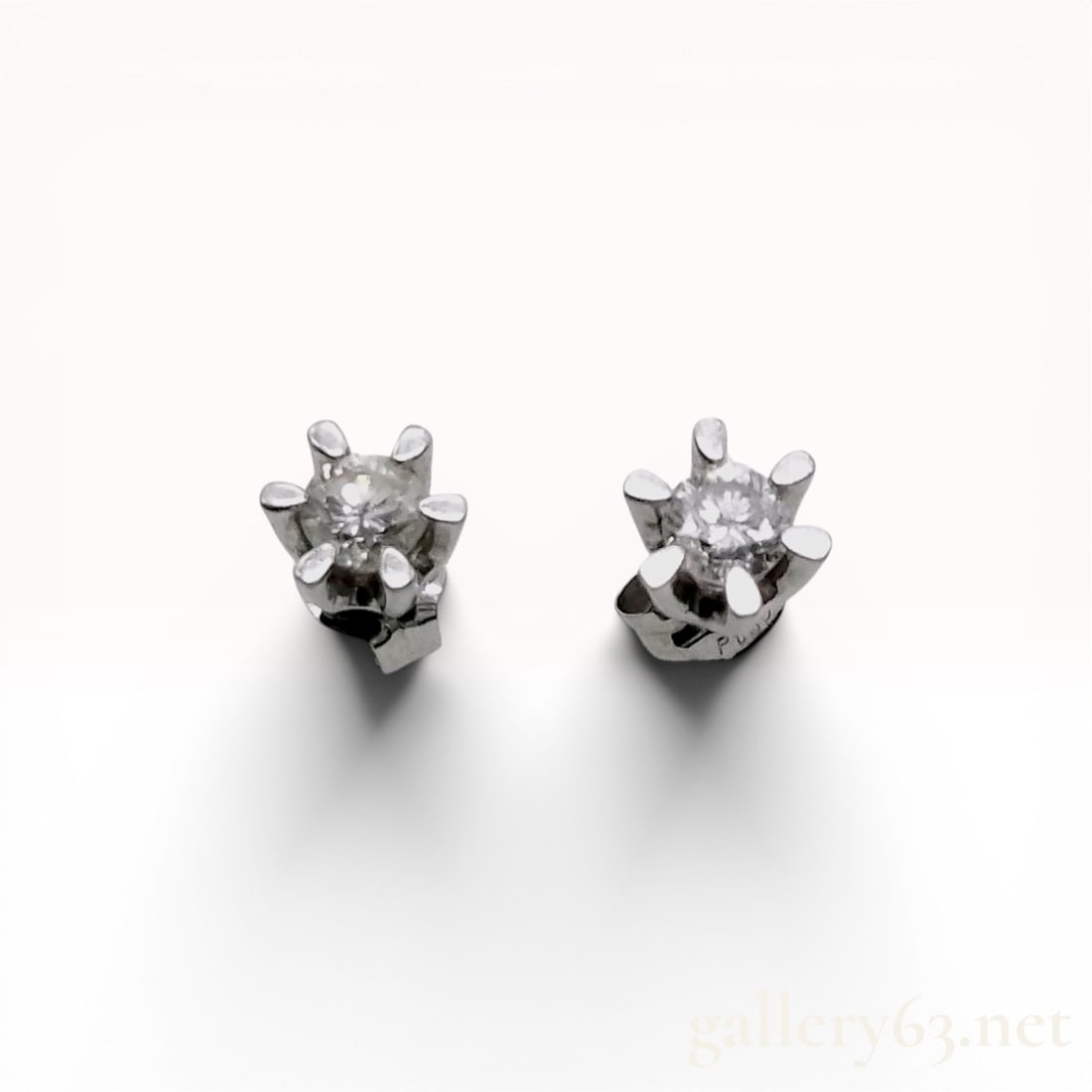 Pair of Pt850 Platinum and Diamond Solitaire Stud Earrings: A matched pair of solitaire stud earrings featuring round brilliant-cut diamonds. Each stone is held in a six-prong basket setting with friction backings. The earring posts and butterfly backs are hal